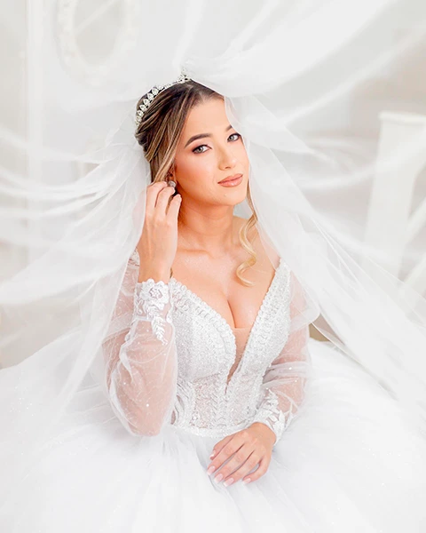 Noiva com véu esvoaçante e vestido de renda