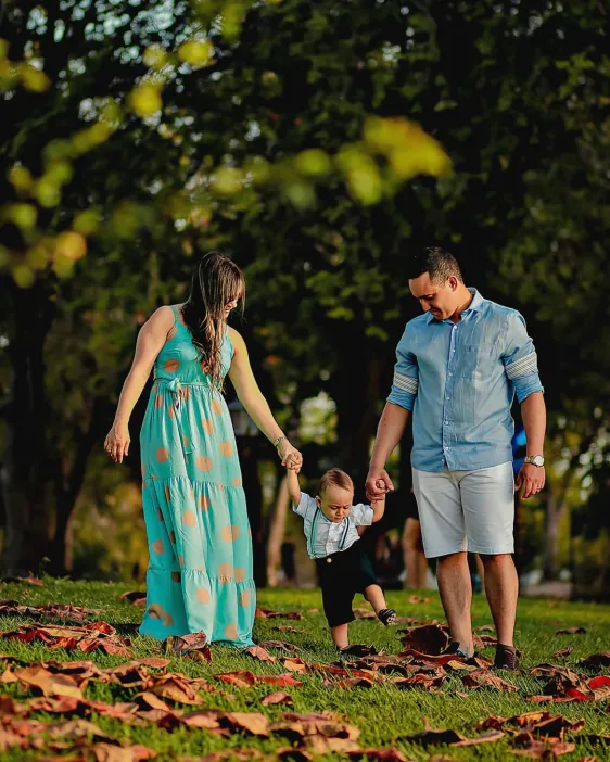 Casal caminhando de mãos dadas com o bebê em um parque