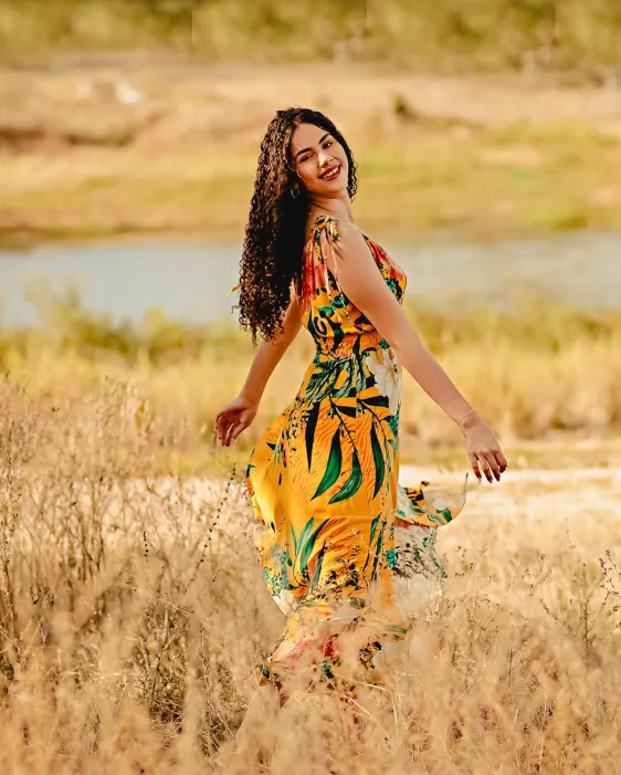 Mulher de vestido estampado girando em um campo