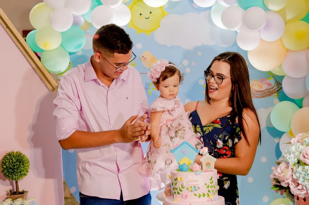 Casal com o bebê em festa de aniversário decorada com balões