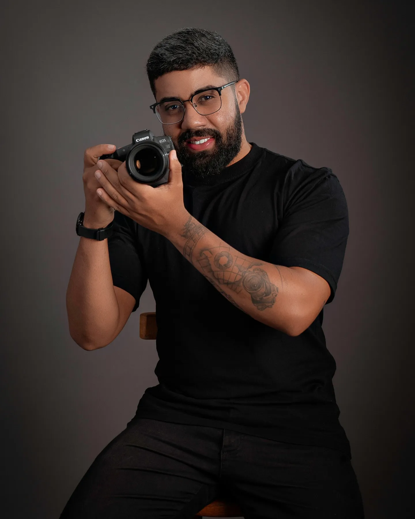 Rafael Souza sorrindo, segurando uma câmera fotográfica